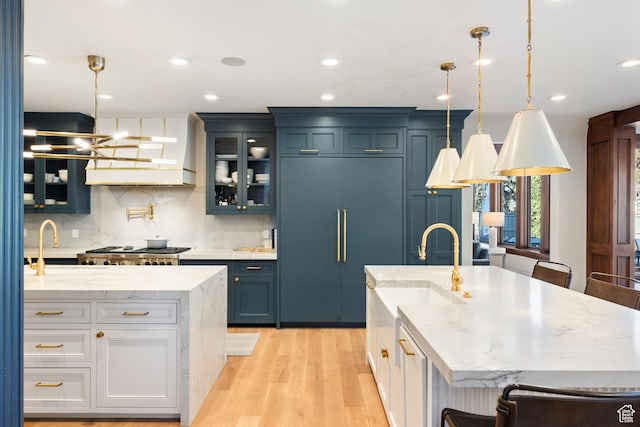 6121 Verness Cv S, Holladay, UT 84121 - kitchen featuring a kitchen island with sink, hanging light fixtures, light stone counters, and paneled refrigerator