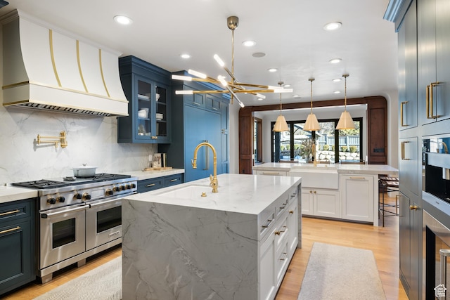 6121 Verness Cv S, Holladay, UT 84121 - kitchen featuring a kitchen island with sink, hanging light fixtures, premium range hood, and appliances with stainless steel finishes