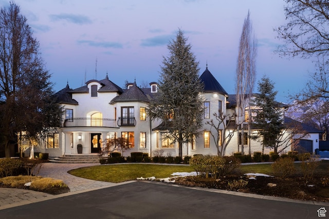 view of front of property with a balcony and a lawn