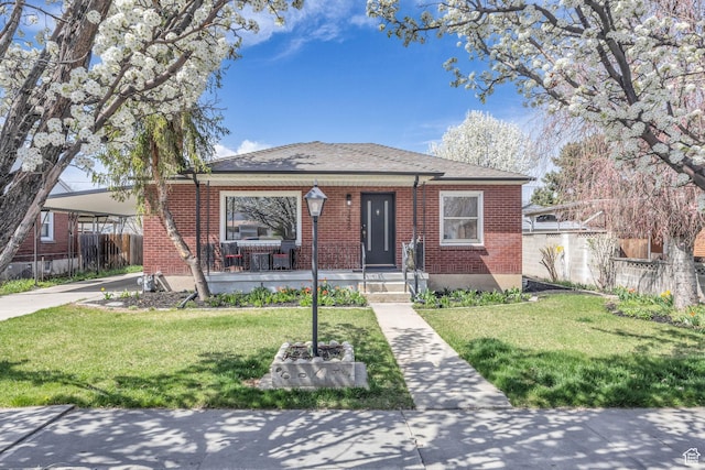 bungalow-style house with a front yard, brick siding, and fence
