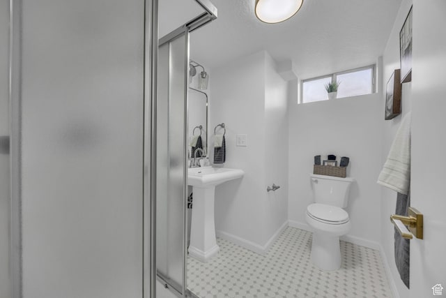bathroom with toilet, a stall shower, and baseboards