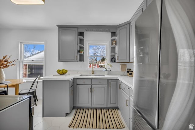 kitchen featuring plenty of natural light, freestanding refrigerator, open shelves, and gray cabinets