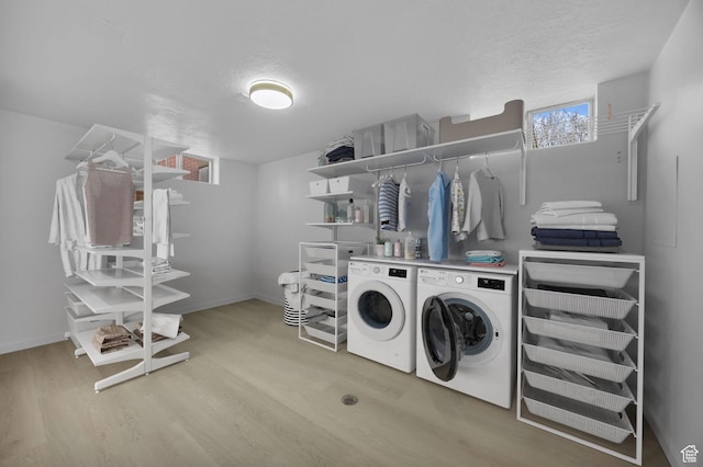 clothes washing area with washer and dryer, light wood-style floors, laundry area, and baseboards