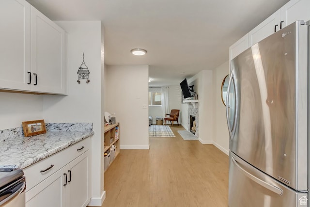 kitchen with light stone countertops, white cabinetry, appliances with stainless steel finishes, and light hardwood / wood-style flooring