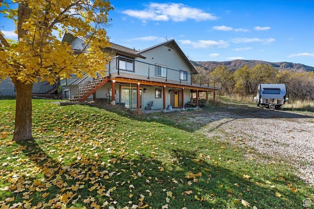 rear view of house featuring a lawn and a deck with mountain view