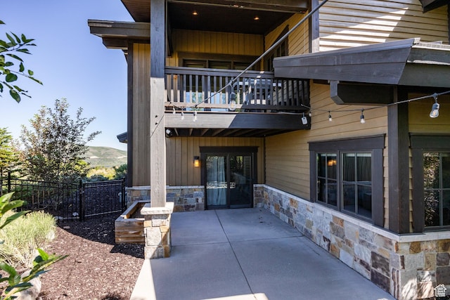10725 N Hideout Trl, Hideout, UT 84036 - rear view of house with stone siding, a balcony, a patio area, and a mountain view