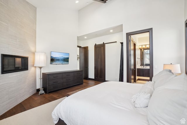 10725 N Hideout Trl, Hideout, UT 84036 - bedroom featuring a barn door, dark wood-type flooring, recessed lighting, a towering ceiling, and connected bathroom