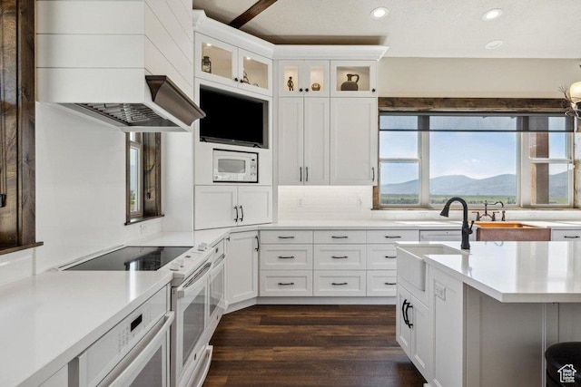 6117 Rocky Ridge Rd N, Peoa, UT 84061 - kitchen featuring dark wood-type flooring, white cabinets, white appliances, decorative backsplash, and wall chimney range hood