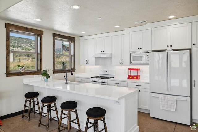 6117 Rocky Ridge Rd N, Peoa, UT 84061 - kitchen featuring white appliances, a breakfast bar, backsplash, white cabinets, and kitchen peninsula