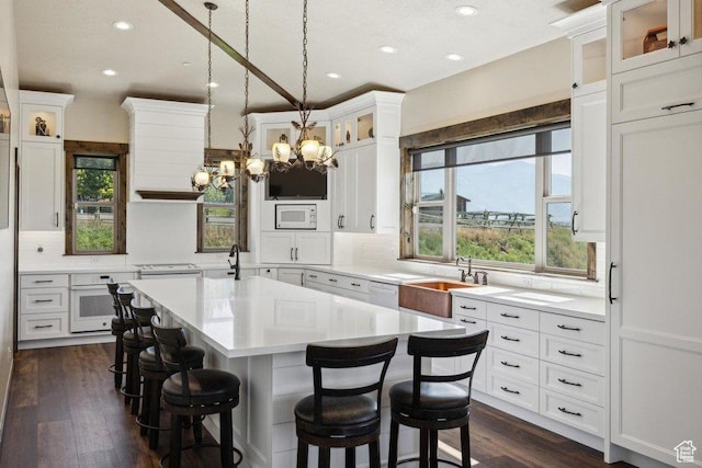 6117 Rocky Ridge Rd N, Peoa, UT 84061 - kitchen with white cabinetry, sink, a healthy amount of sunlight, a center island with sink, and white appliances