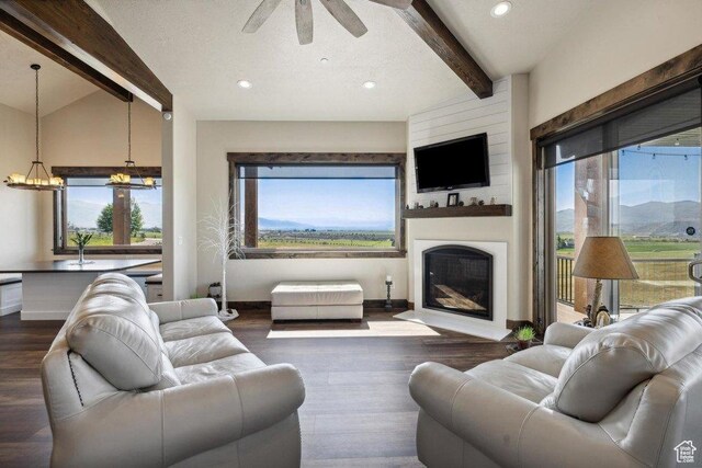6117 Rocky Ridge Rd N, Peoa, UT 84061 - living room with ceiling fan with notable chandelier, vaulted ceiling with beams, a large fireplace, dark wood-type flooring, and a textured ceiling