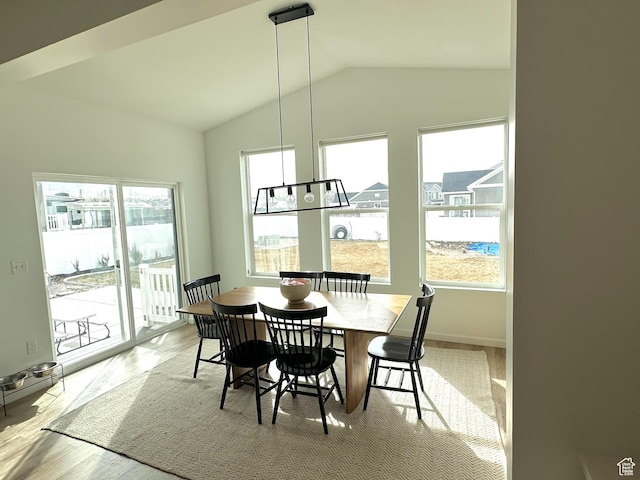 dining area with light hardwood / wood-style flooring and vaulted ceiling