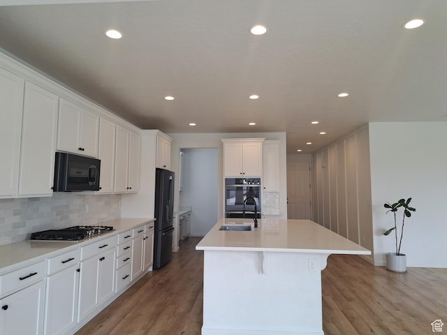 128 Tram Rock Rd, Lake Point, UT 84074 - kitchen with black appliances, a sink, white cabinetry, a kitchen island with sink, and light wood-style floors