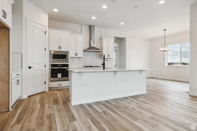 6199 W Wapiti Ridge Ln Unit 333, Herriman, UT 84096 - kitchen with a kitchen bar, a center island with sink, wall chimney range hood, stainless steel appliances, and white cabinets