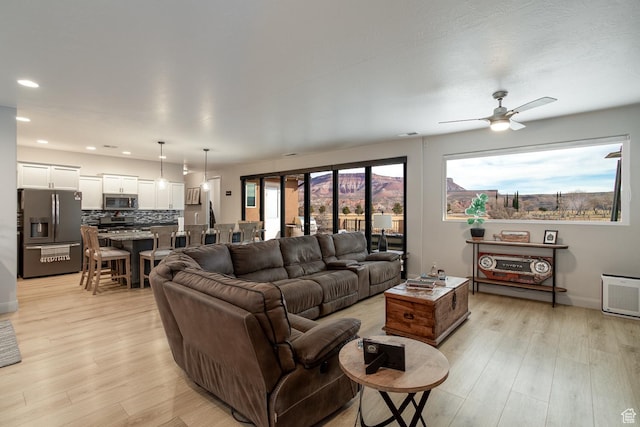 living area featuring light wood finished floors, a ceiling fan, recessed lighting, and baseboards