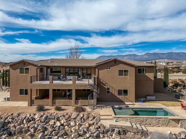 back of house featuring stairs, a patio area, stucco siding, an outdoor pool, and an in-ground hot tub