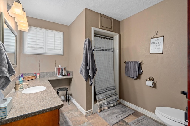 full bath featuring vanity, curtained shower, toilet, baseboards, and a textured ceiling