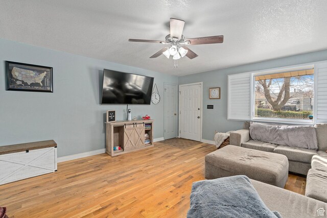 living room with a textured ceiling, baseboards, ceiling fan, and wood finished floors