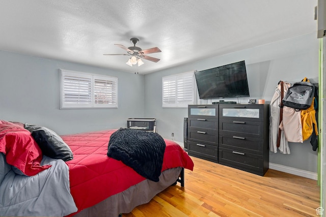 bedroom featuring baseboards, a ceiling fan, light wood finished floors, and a textured ceiling