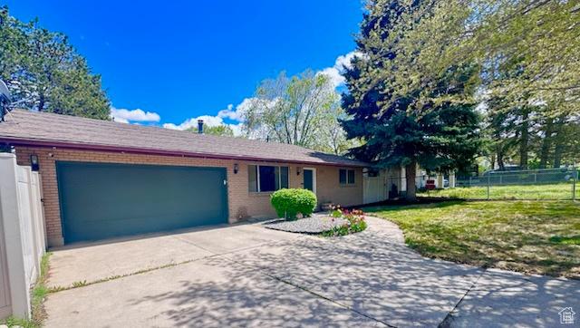 single story home featuring brick siding, driveway, fence, and a garage