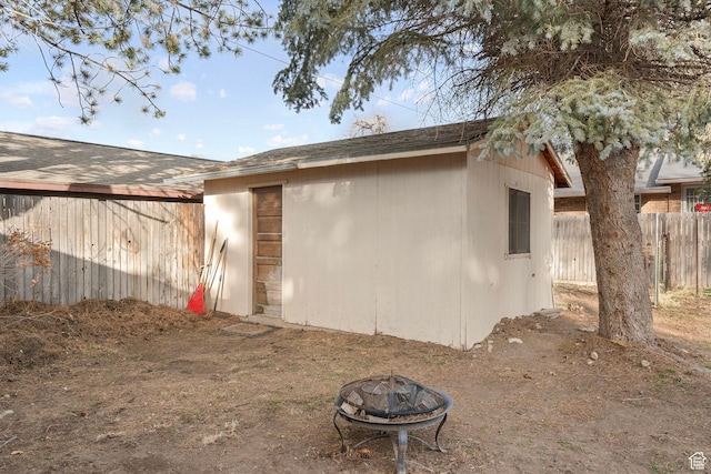 exterior space with fence, an outdoor structure, and a fire pit