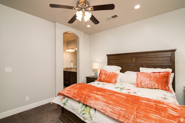 bedroom with connected bathroom, ceiling fan, and dark colored carpet