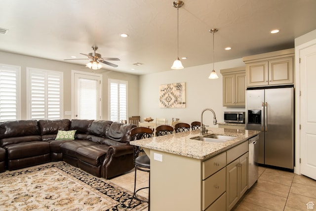 kitchen featuring appliances with stainless steel finishes, sink, a kitchen bar, a kitchen island with sink, and cream cabinets