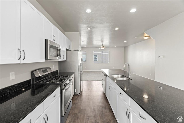 kitchen featuring appliances with stainless steel finishes, sink, white cabinets, and dark stone counters