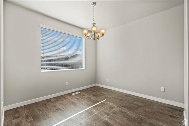empty room with dark hardwood / wood-style flooring and a chandelier