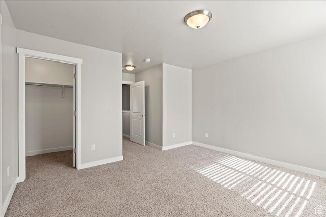 unfurnished bedroom featuring a walk in closet, a closet, and light carpet