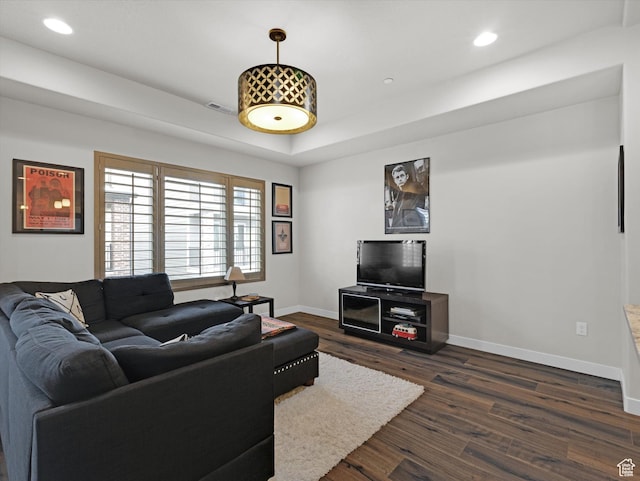 living room featuring a tray ceiling and dark wood-type flooring