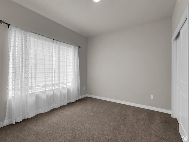 unfurnished bedroom featuring a closet and dark colored carpet