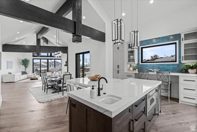 11432 N Fox Hollow Ct Unit 121, Hideout, UT 84036 - kitchen with stainless steel microwave, a sink, beam ceiling, light wood finished floors, and glass insert cabinets