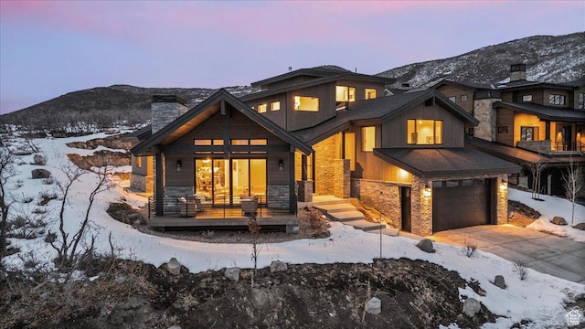 11432 N Fox Hollow Ct Unit 121, Hideout, UT 84036 - snow covered house with stone siding, concrete driveway, a mountain view, and an attached garage