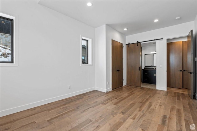11432 N Fox Hollow Ct Unit 121, Hideout, UT 84036 - unfurnished bedroom featuring recessed lighting, baseboards, a barn door, ensuite bathroom, and wood finished floors