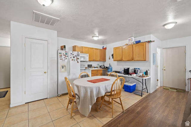 kitchen featuring light countertops, a textured ceiling, visible vents, and white appliances