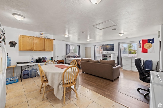 dining area with attic access, a textured ceiling, and light tile patterned flooring