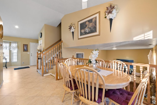 dining space featuring high vaulted ceiling, stairway, baseboards, and light tile patterned floors