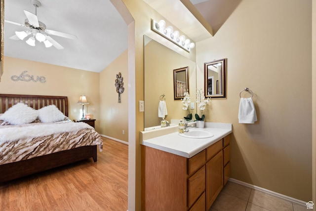 bedroom featuring arched walkways, lofted ceiling, a sink, and baseboards