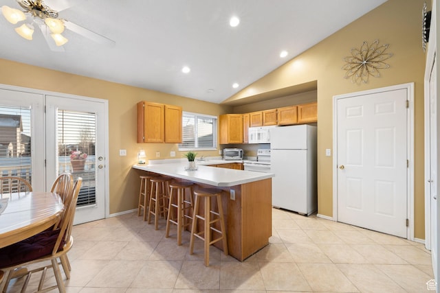 kitchen with white appliances, light countertops, a kitchen bar, a peninsula, and lofted ceiling