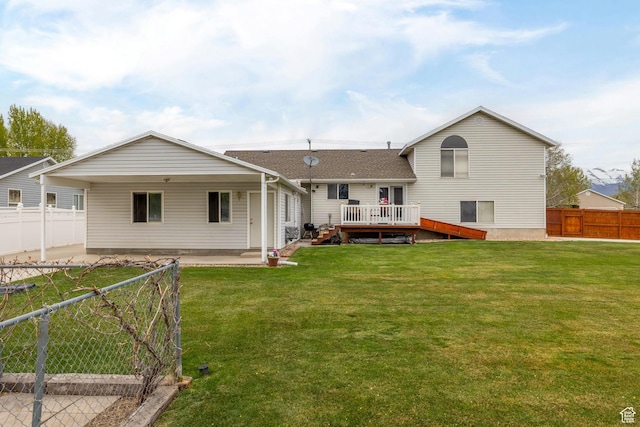 rear view of property with a lawn, a shingled roof, a fenced backyard, and a deck