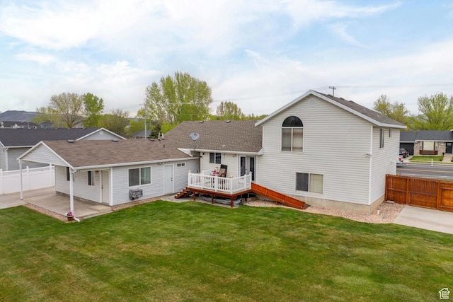rear view of house with a wooden deck, a yard, a patio area, and fence