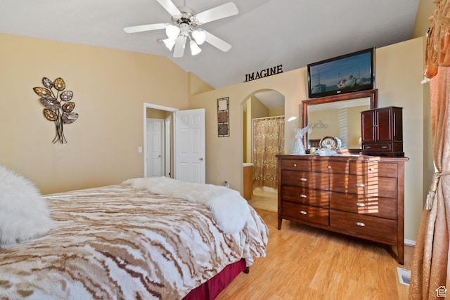 bedroom featuring vaulted ceiling, visible vents, connected bathroom, arched walkways, and light wood-type flooring