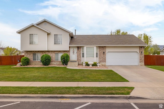 tri-level home featuring brick siding, a front yard, and fence