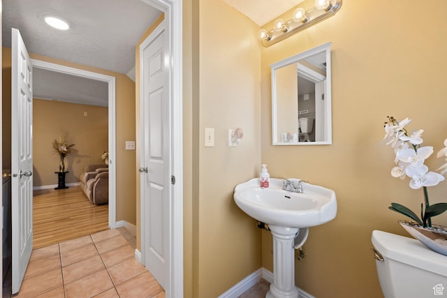 bathroom with baseboards, tile patterned flooring, and toilet