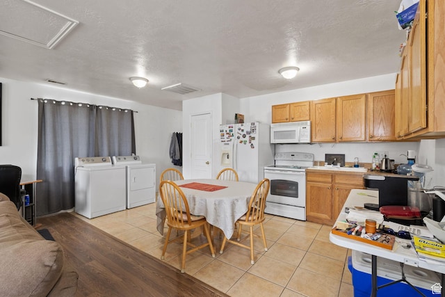 kitchen featuring washing machine and clothes dryer, white appliances, light tile patterned floors, light countertops, and visible vents