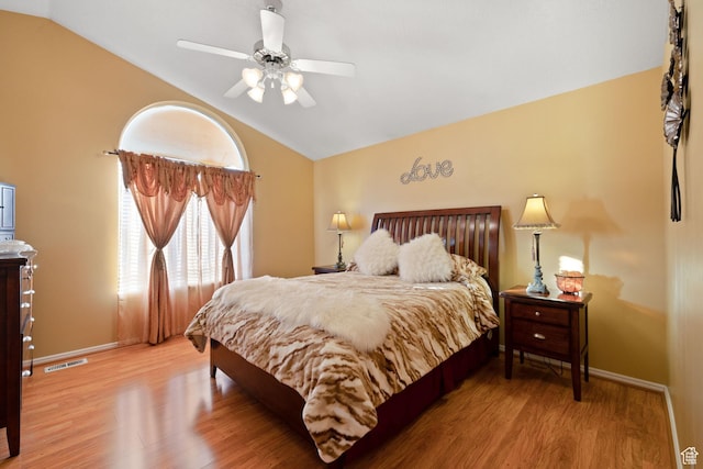 bedroom with vaulted ceiling, wood finished floors, visible vents, and baseboards
