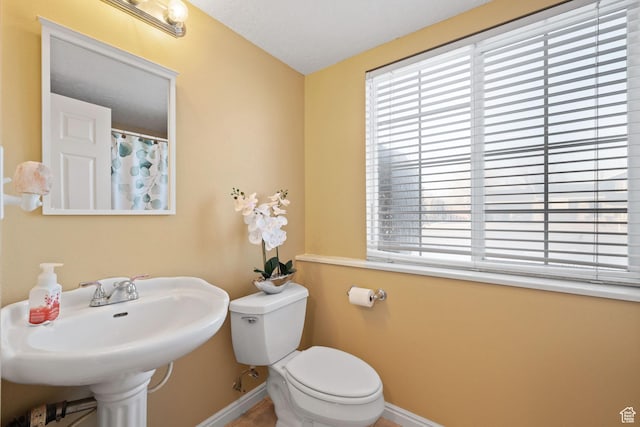 full bath featuring baseboards, toilet, a sink, and curtained shower