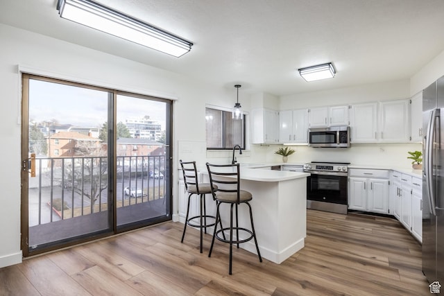 245 N Vine St W Unit 501, Salt Lake City, UT 84103 - kitchen with white cabinetry, appliances with stainless steel finishes, decorative light fixtures, and a breakfast bar area