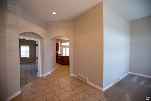 hallway with a wealth of natural light, arched walkways, and visible vents